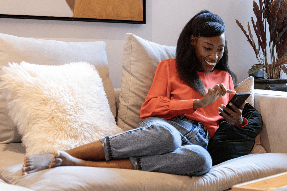 Women laying on couch smiling at her phone.