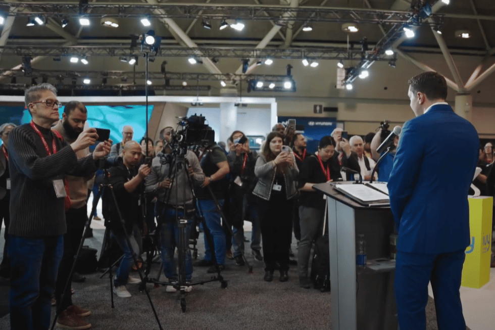 CEO of Ivy Charging Network, Michael Kitchen, delivering an announcement at the AutoShow in Toronto with press taking photos.